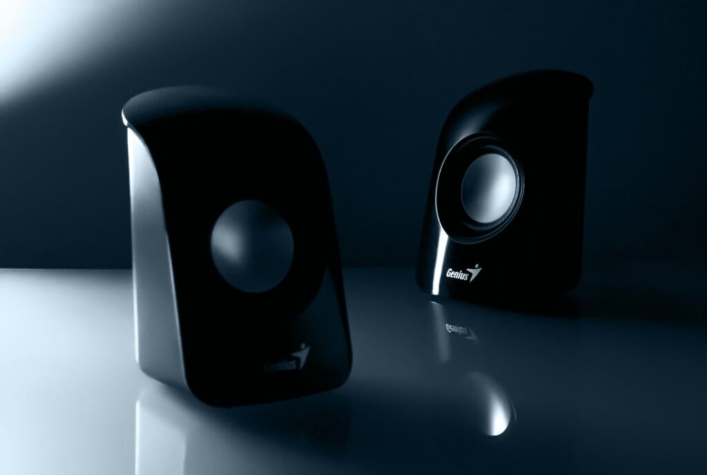 Stylish black desktop speakers with reflective design for enhanced audio experience.